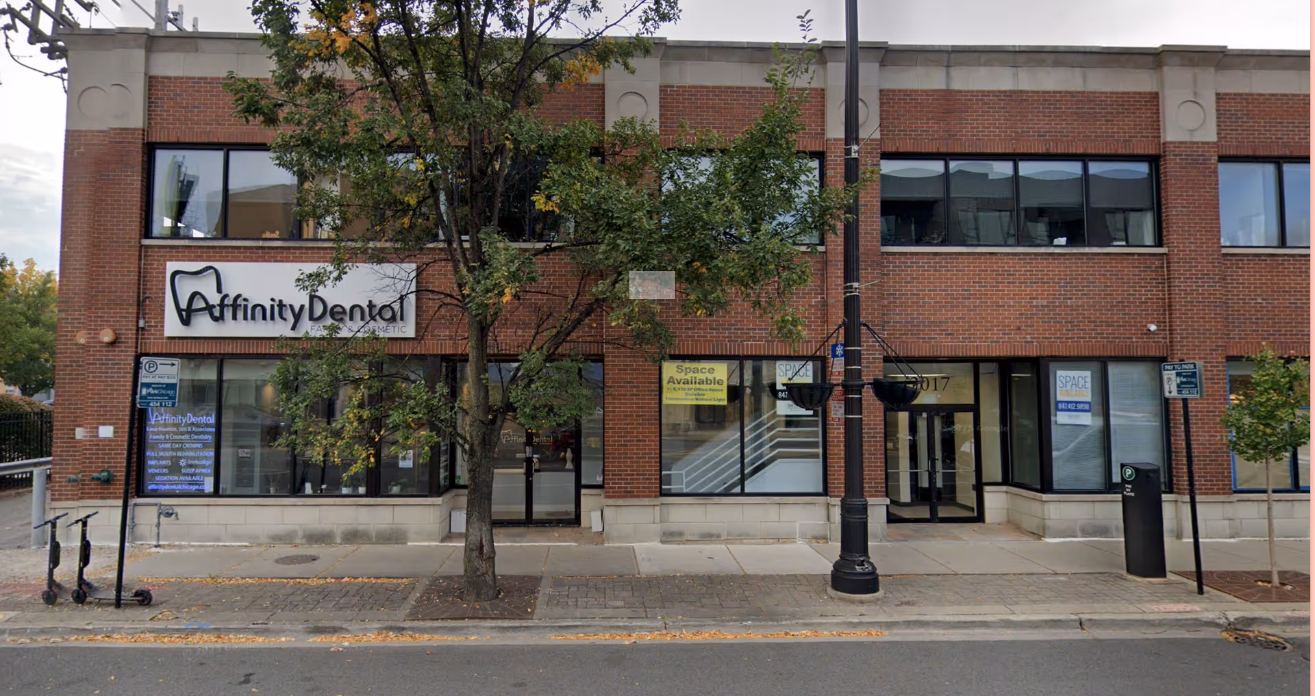 Brick storefront building with Affinity Dental sign, large windows, and a tree.