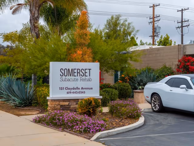 Entrance sign reading 'Somerset Subacute Rehab' at 151 Claydelle Avenue surrounded by landscaping and a parked white car.