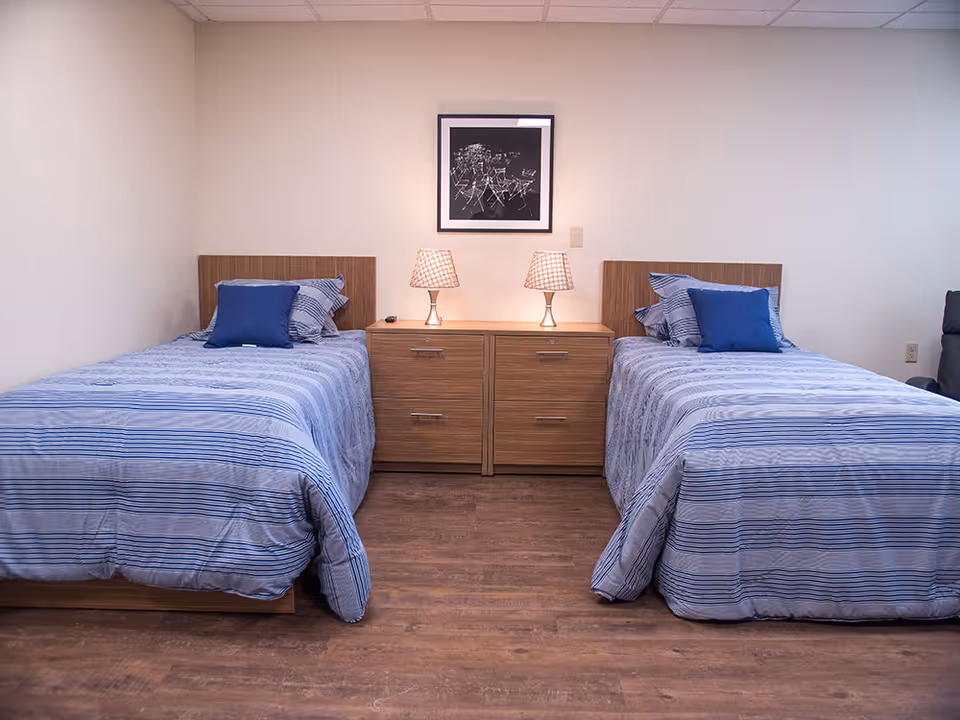 Twin beds with blue striped bedding flank a central nightstand with lamps.
