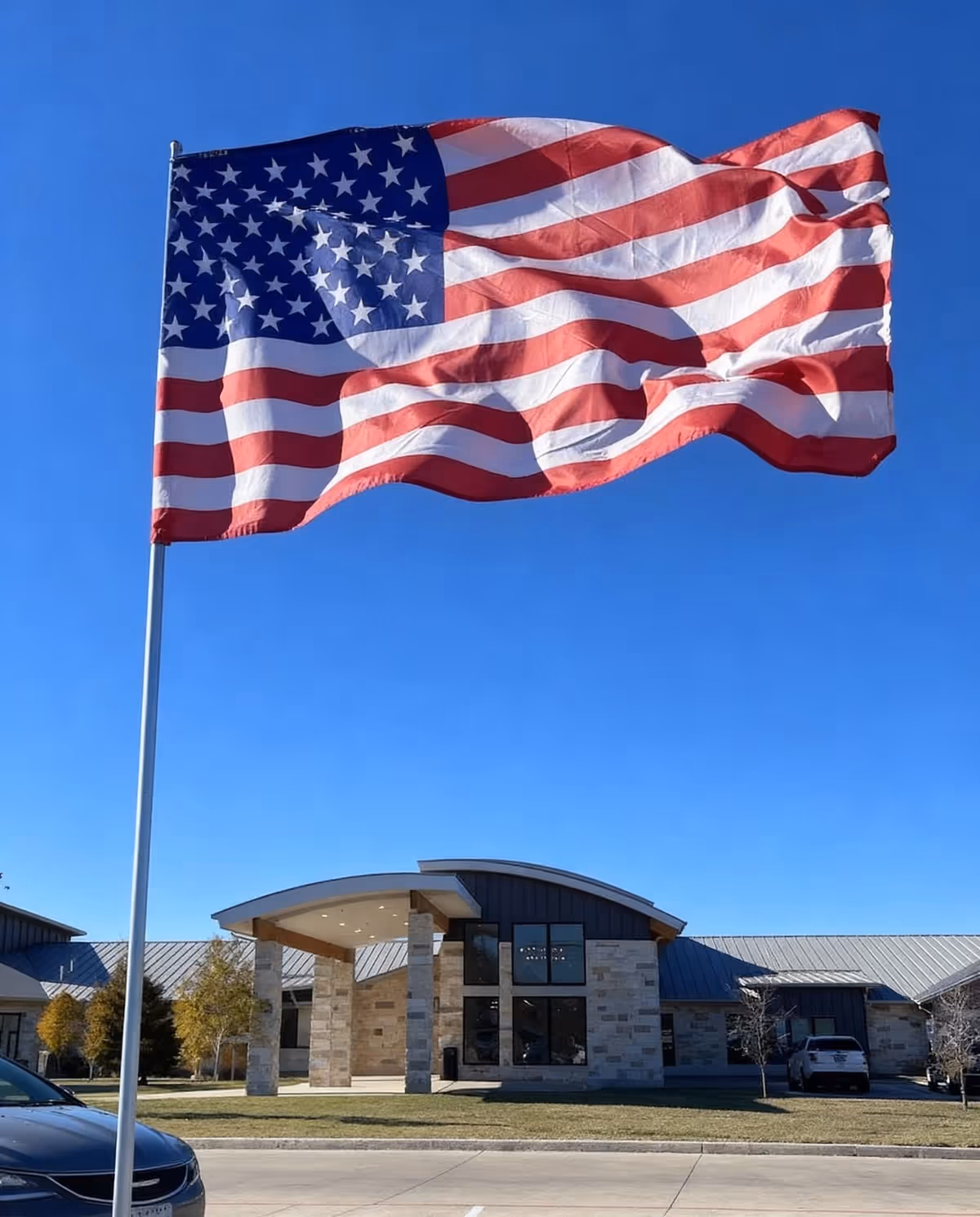 American flag waves in front of a modern senior living facility entrance
