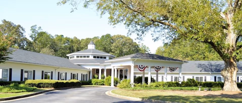 Mulberry Grove Senior Living exterior, white low-rise building with a covered entrance and landscaping.