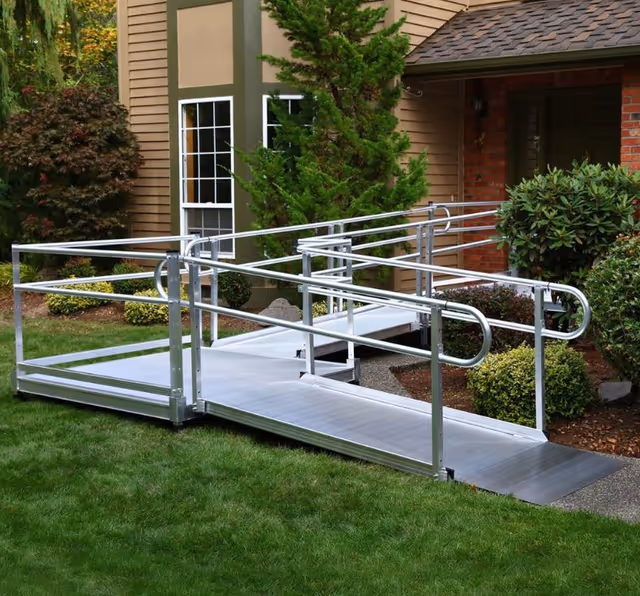 Silver metal ramp leads to a building entrance, surrounded by greenery.