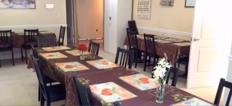 A dining room with several tables set with brown tablecloths and flower centerpieces.