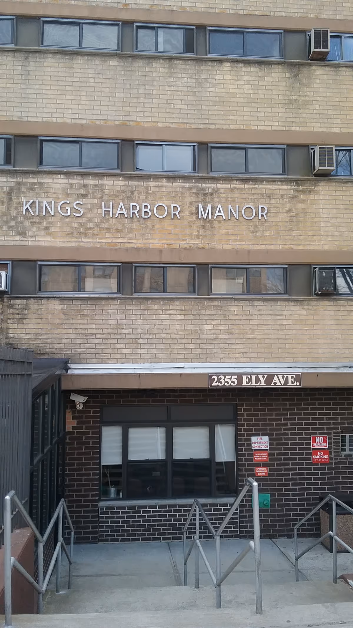 Exterior view of Kings Harbor Manor building entrance with stairs and signage.