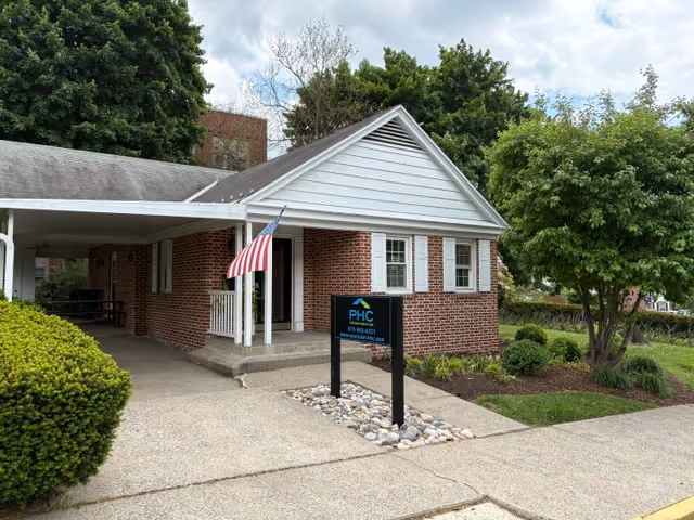 Brick building of Precision Health Care with American flag at front entrance.