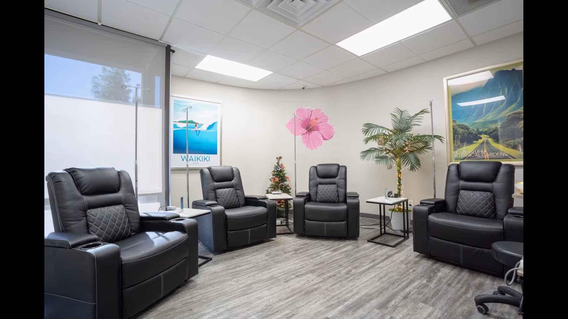 Interior lounge with black leather recliners, plants, and wall posters in a senior facility.