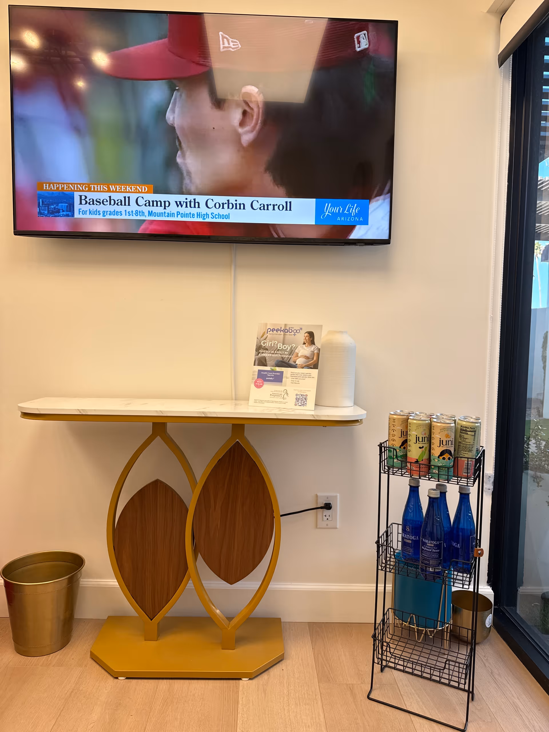 Flat-screen TV on wall above marble console, with a beverage rack beside glass doors.