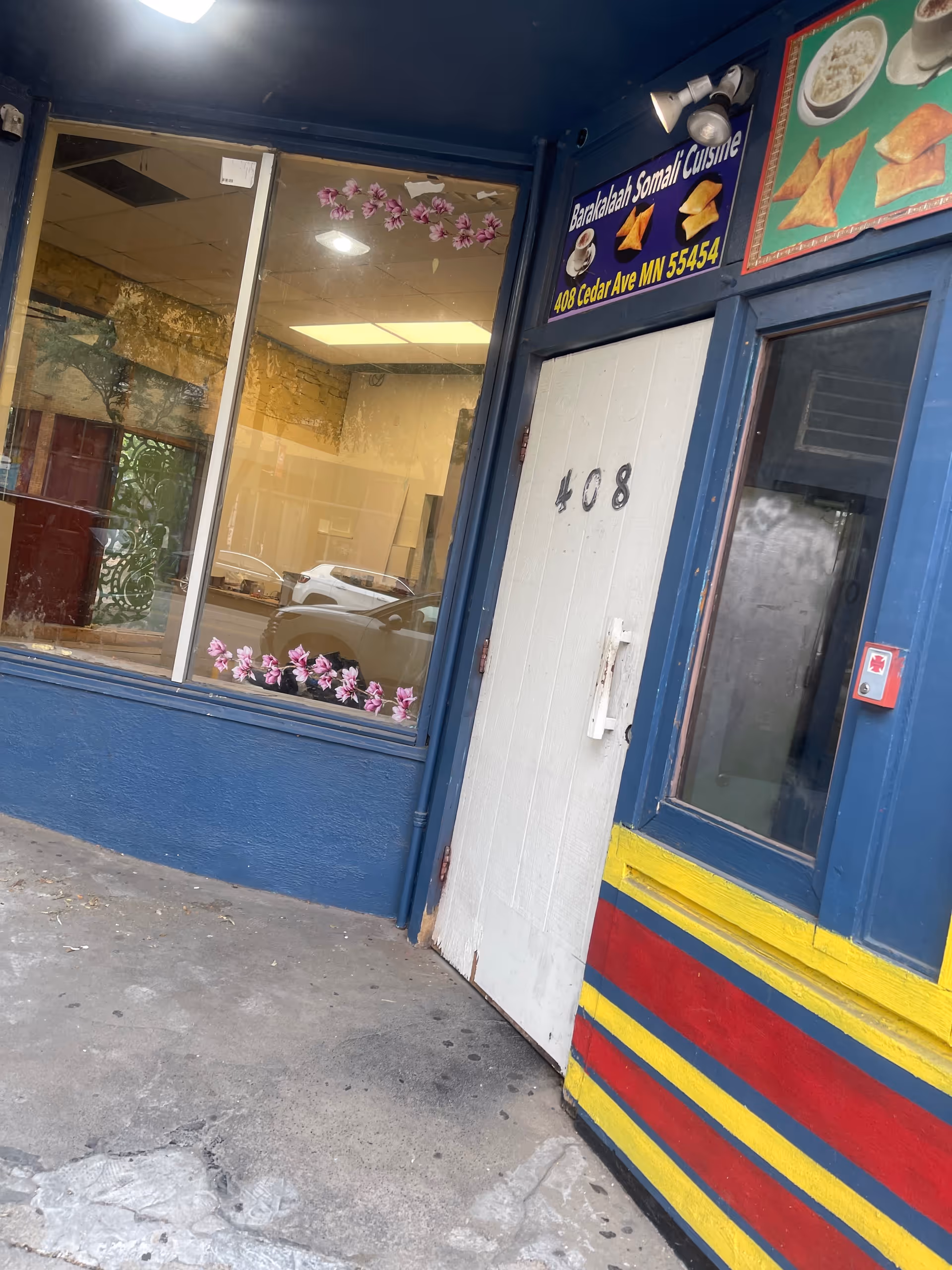 Blue-framed storefront with a white door, large window, and a restaurant sign above.