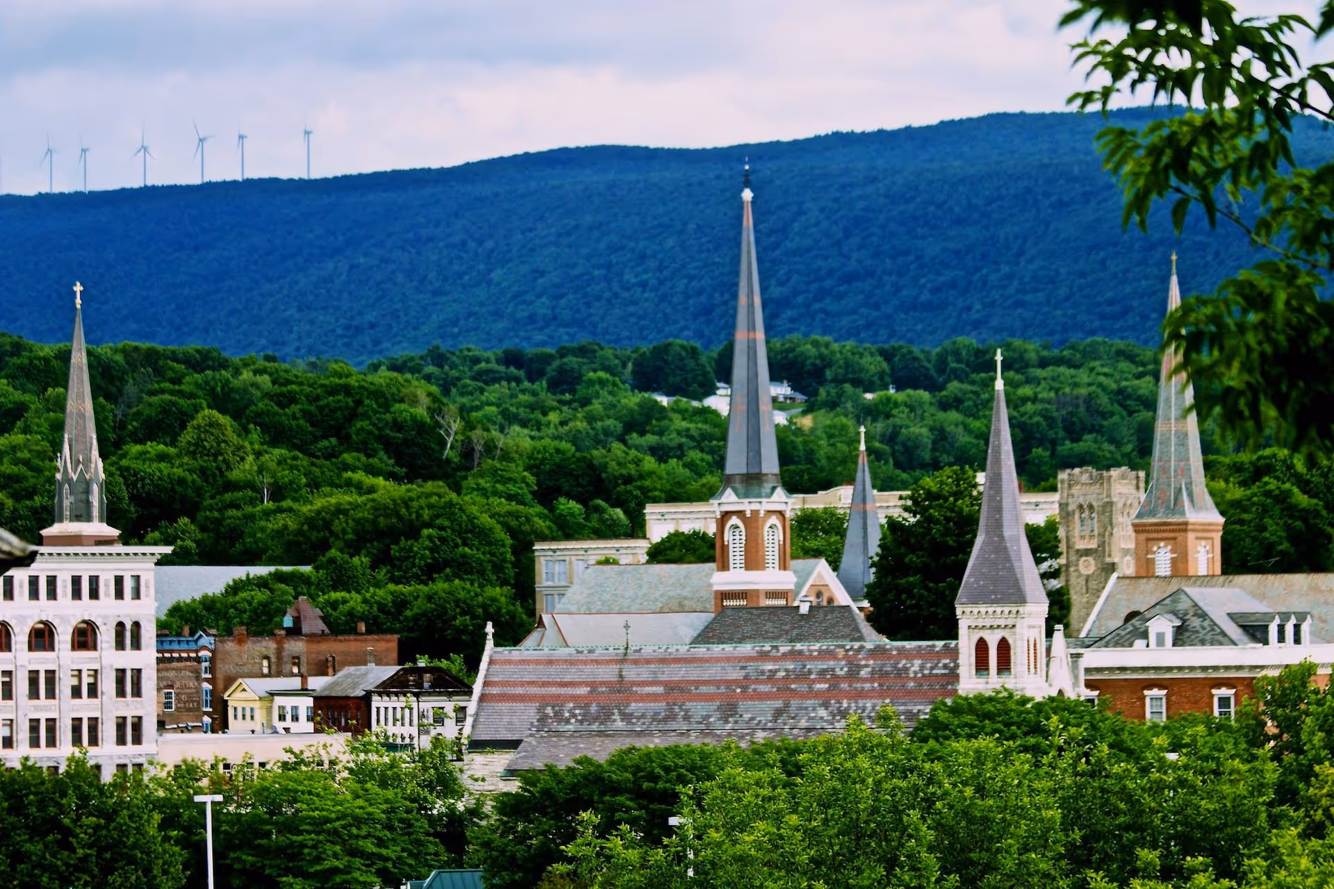 View of a town with tall church spires and forested hills.