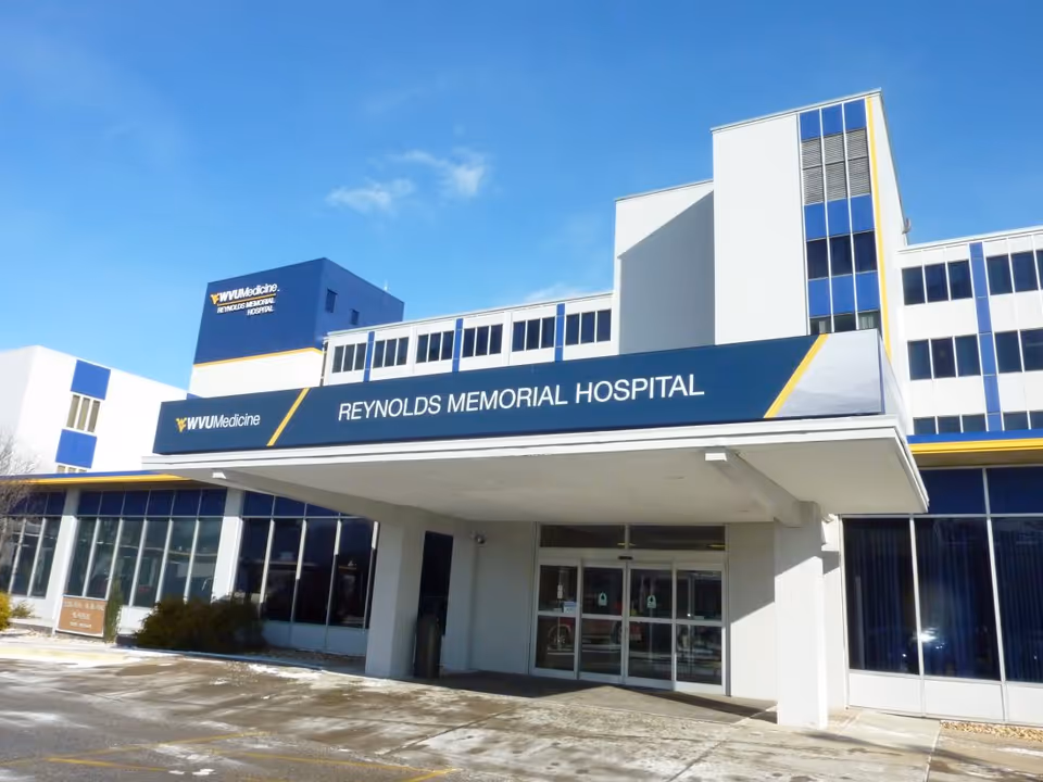 Front exterior of Reynolds Memorial Hospital with glass entrance and blue signage.