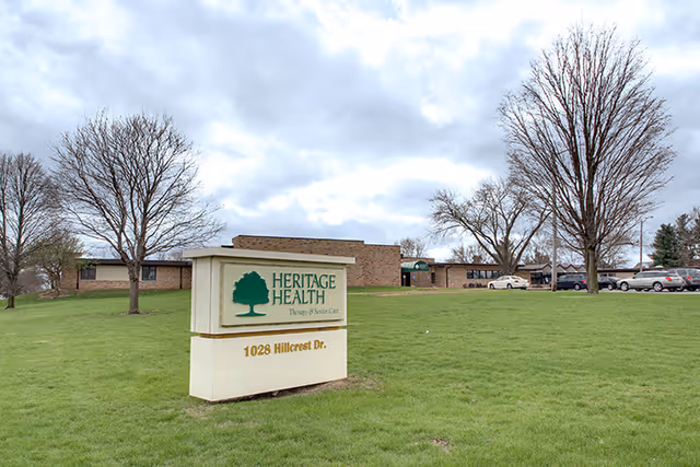 Exterior view of Heritage Health facility with a sign and parking lot.