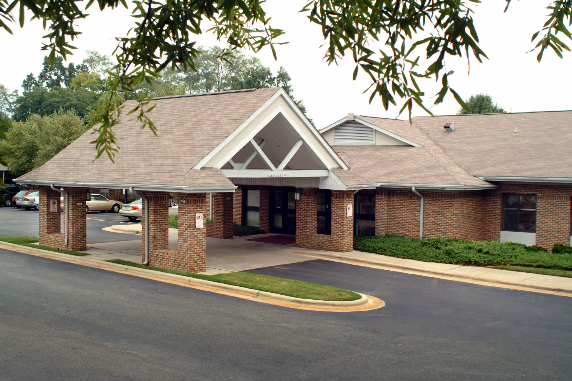 Exterior view of Brantwood NH & Retirement Center entrance with brick columns and driveway.