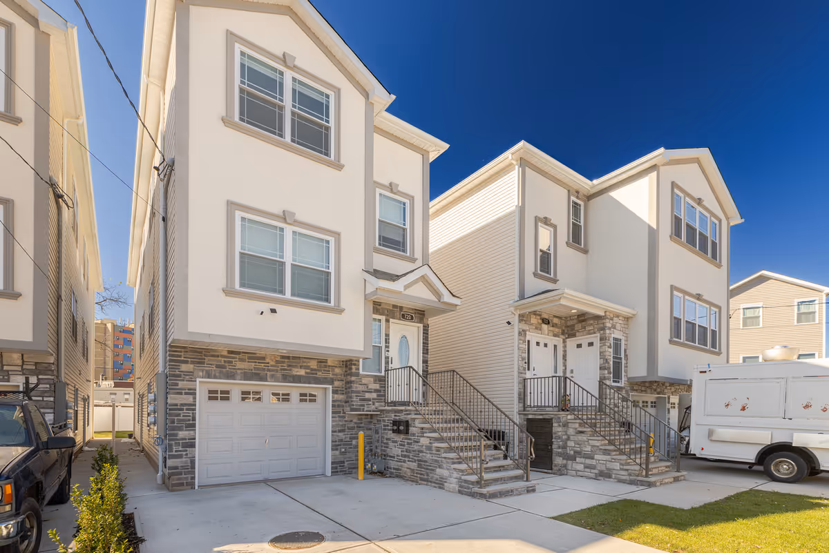 Two modern townhome-style buildings with stone accents, garages, and stairs to entry doors.