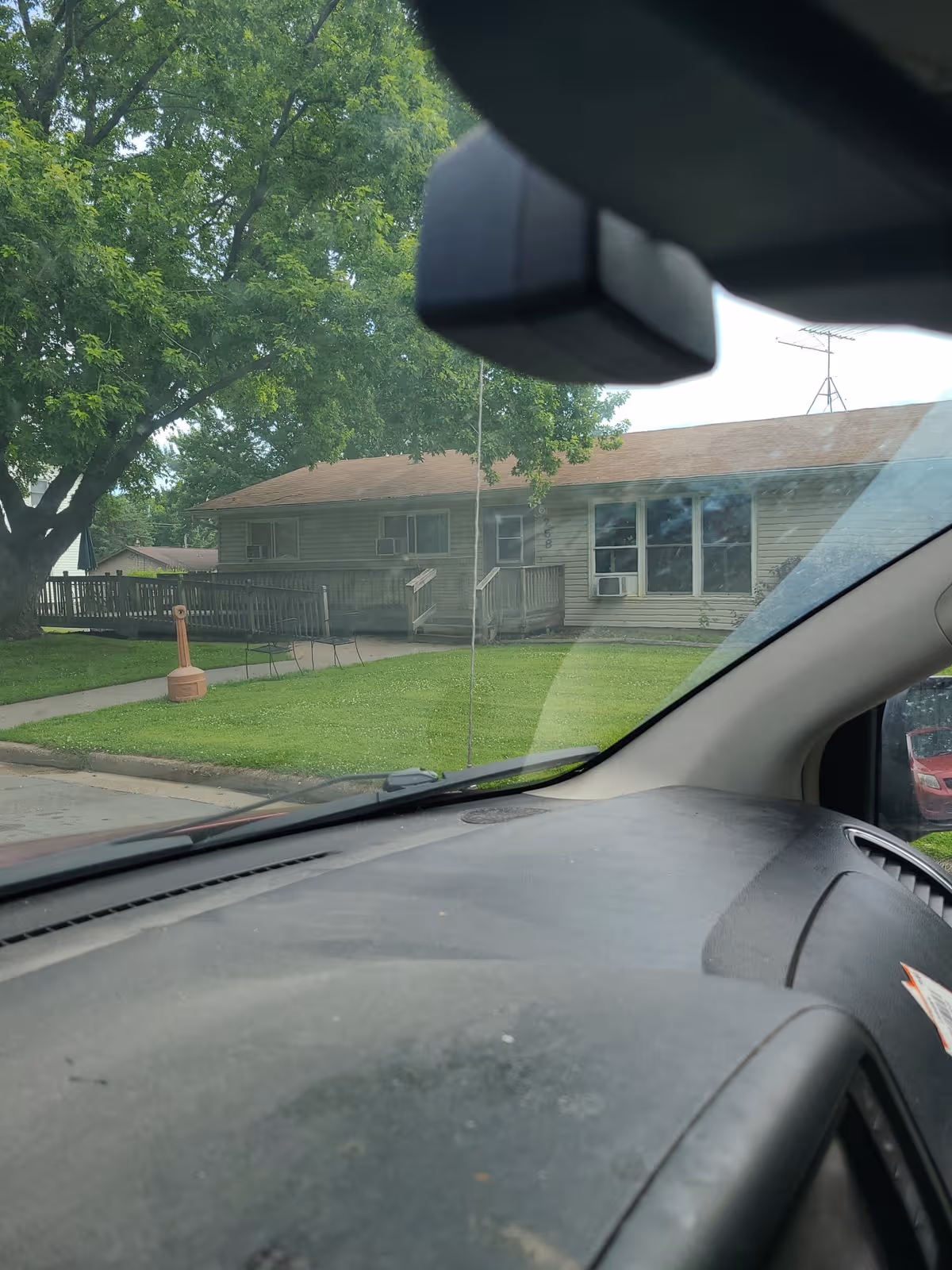 View from inside a car shows Brotoloc Health Care Systems facility front with porch and lawn.