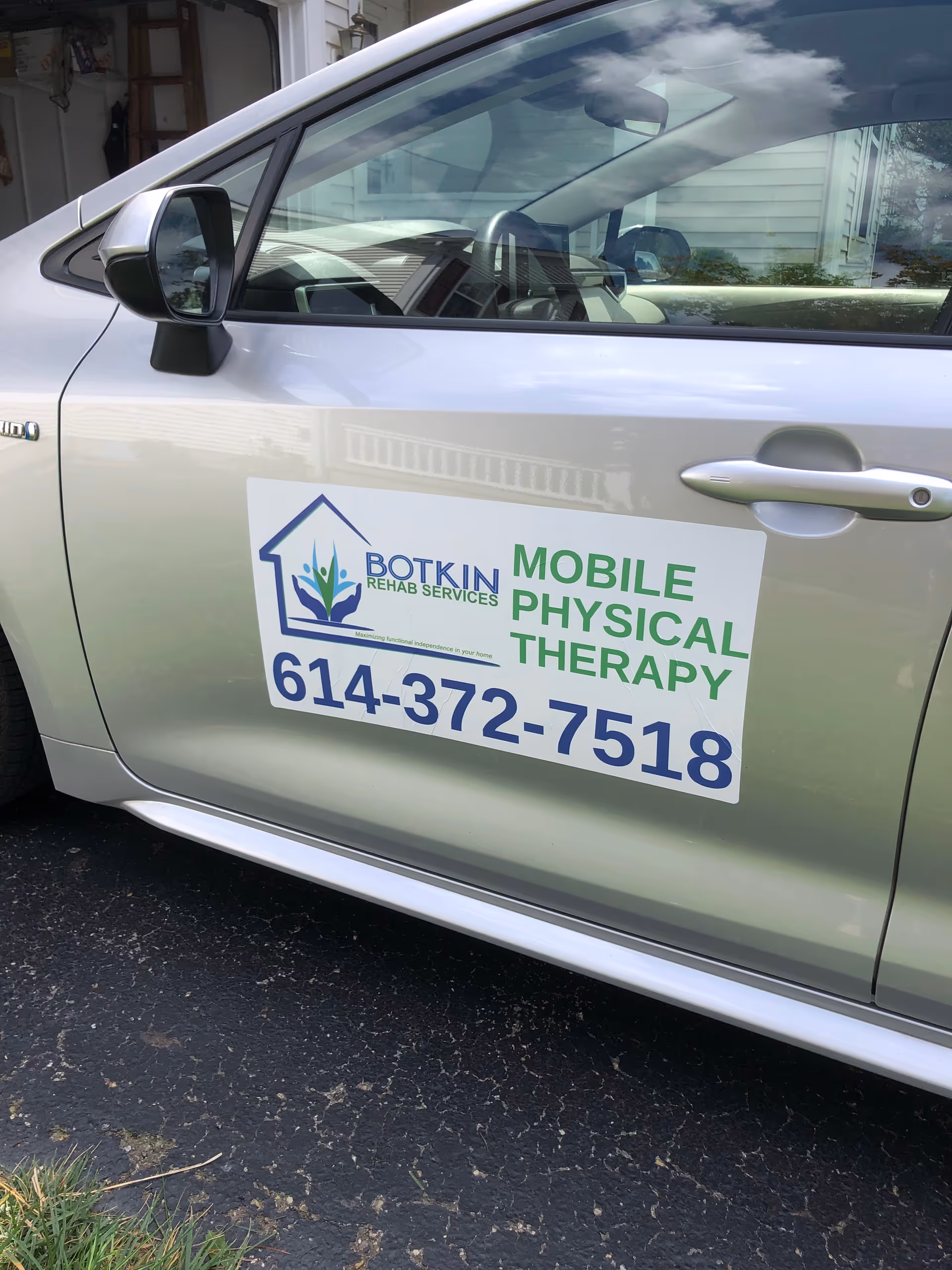 Side view of a car displaying Botkin Rehab Services' mobile physical therapy sign.