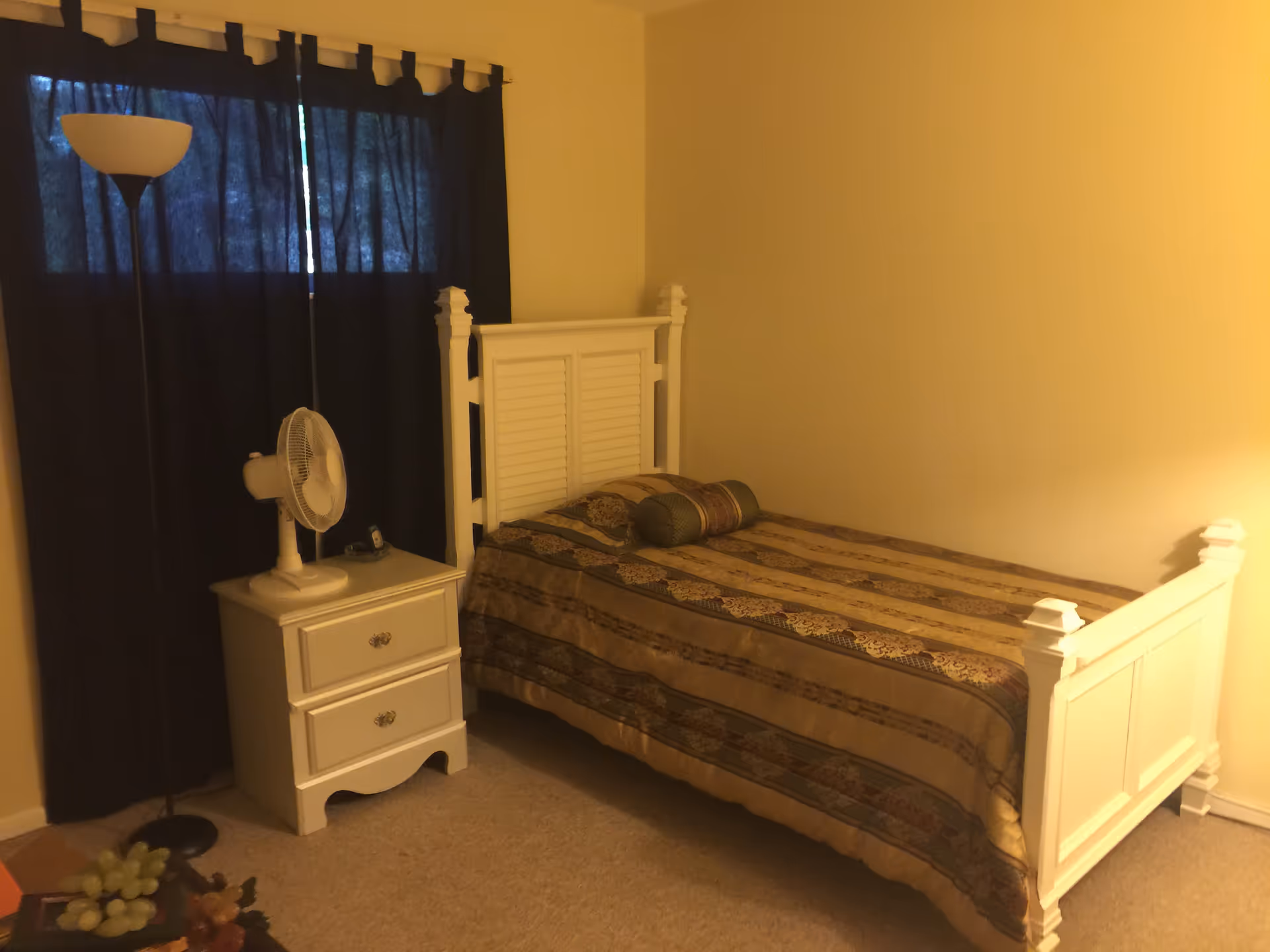 White wooden bed with matching headboard and nightstand in a cozy bedroom.