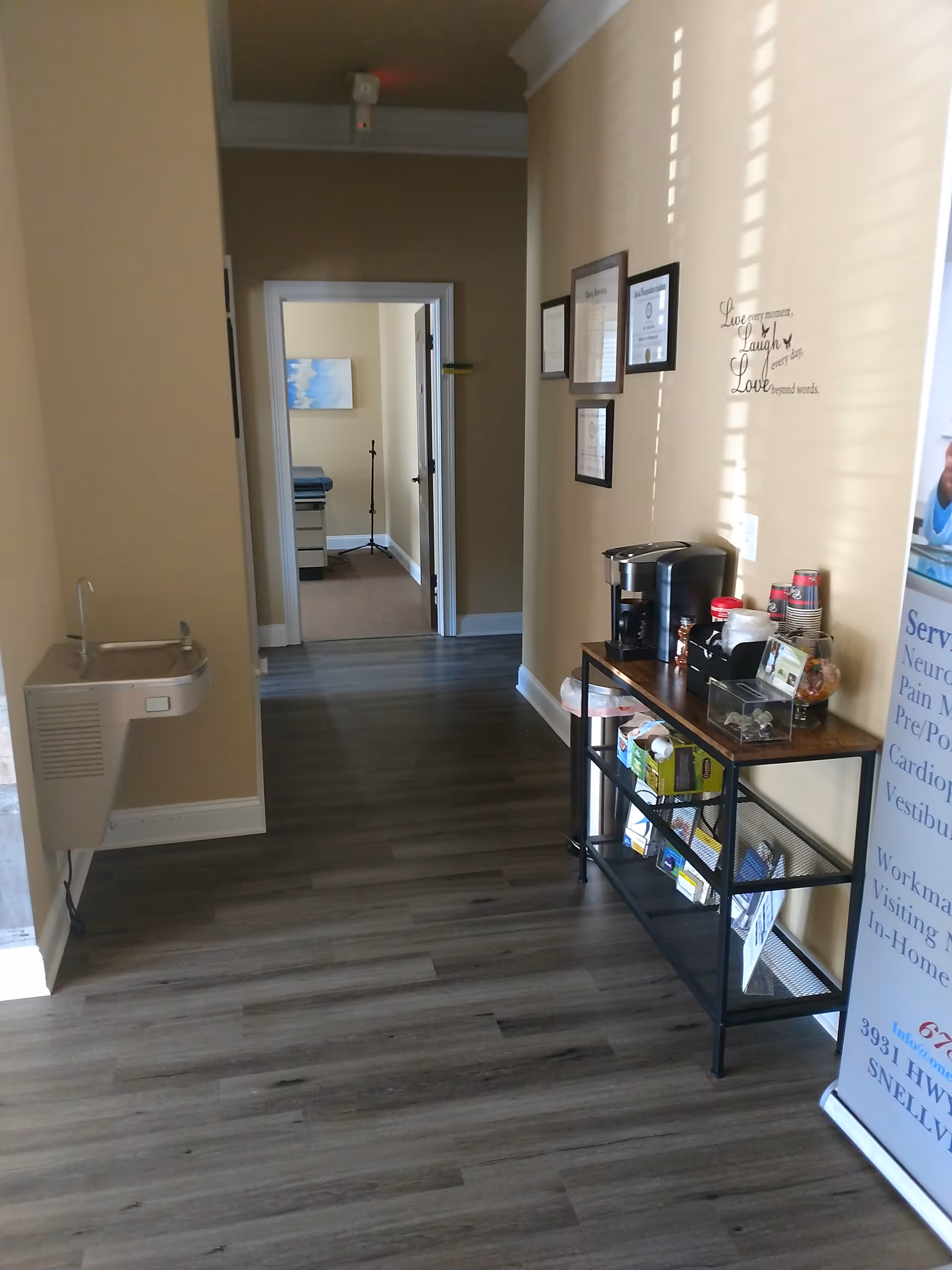 Interior hallway of a senior facility with a coffee station, framed certificates, and a water fountain.