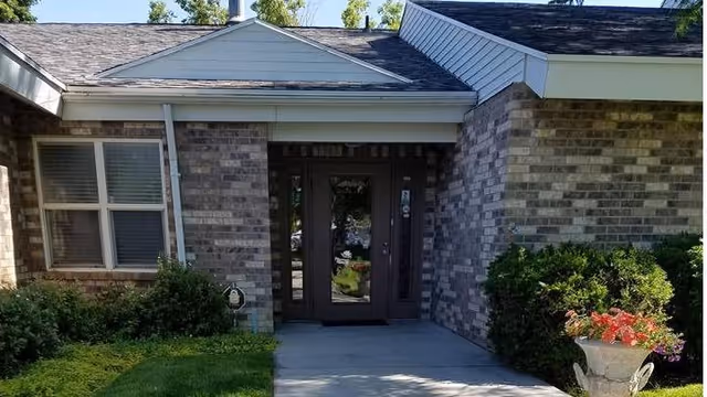 Front entrance of Country Oaks Assisted Living with brick facade, glass doors, and shrubs.