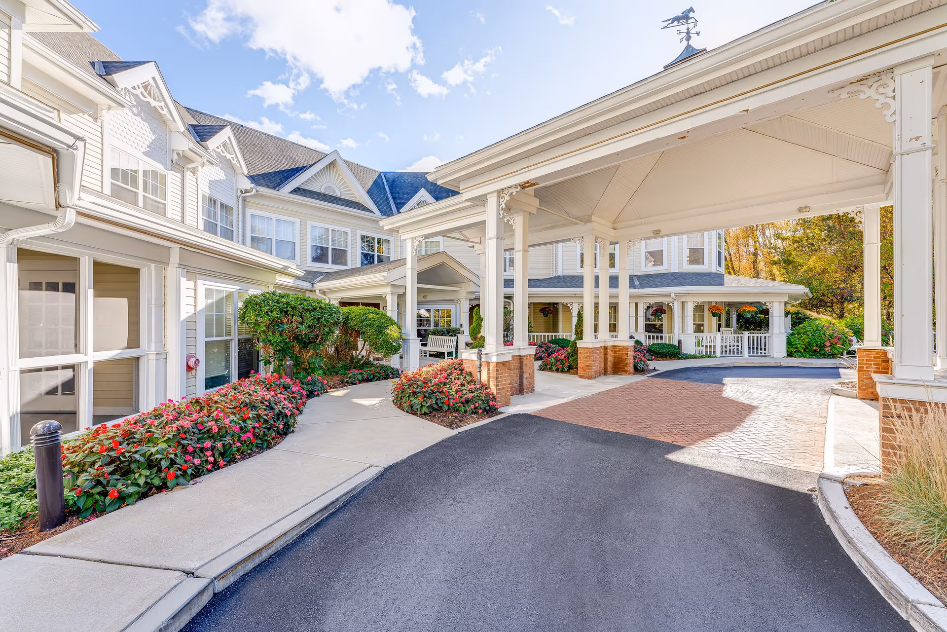Sunrise of Wayland building exterior with a curved driveway, covered entrance, and landscaped walkway.