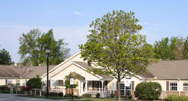 Exterior view of Arden Courts Westlake senior living facility with trees and walkway.
