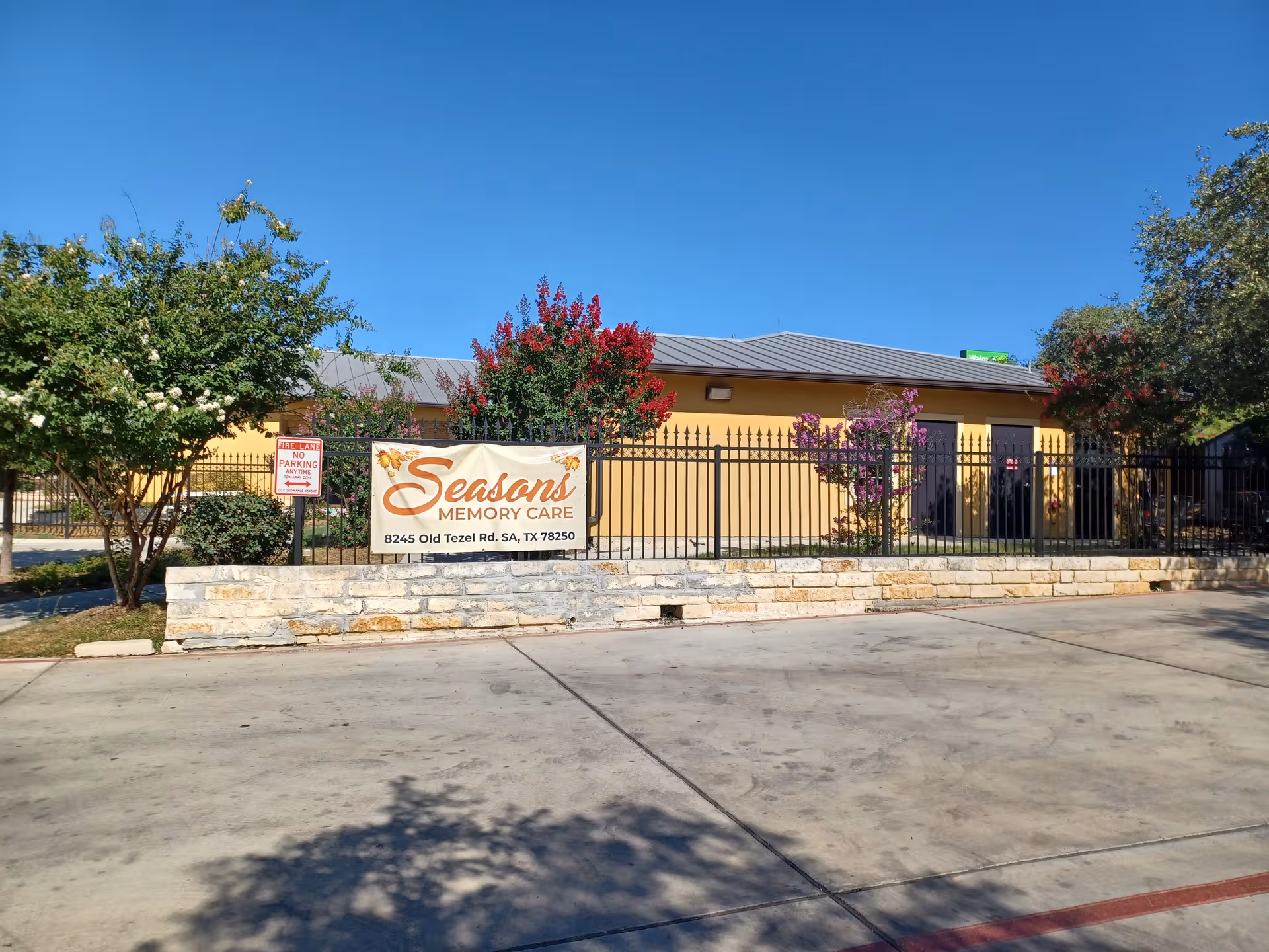 Exterior view of Seasons Memory Care building with fence and sign.