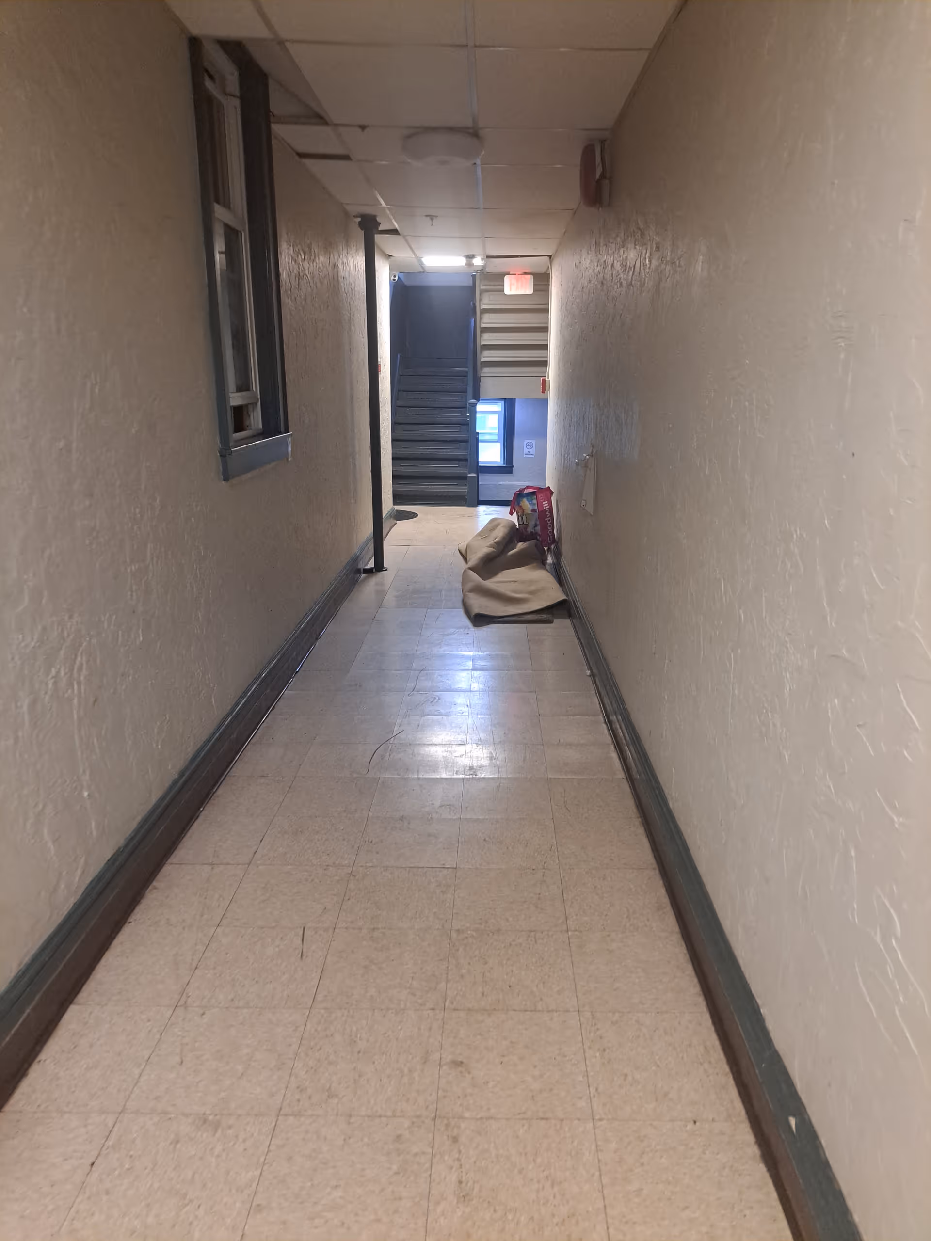 Long interior hallway with stairs at the far end and items on the floor.