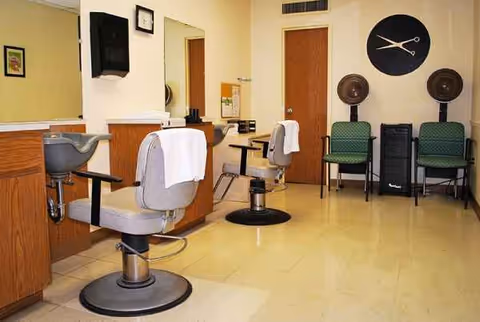 Barber chairs and hairdressing equipment line a salon area inside a senior living facility.
