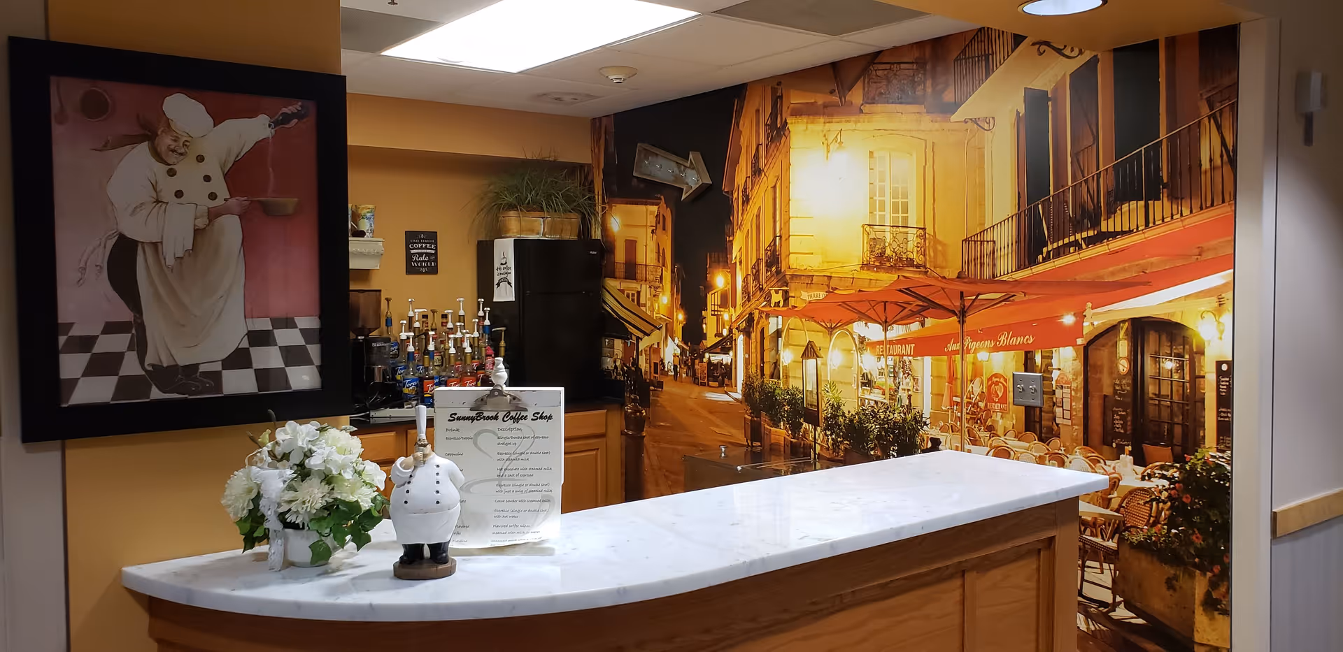 Reception desk with marble counter, flowers, chef artwork, and a Paris street mural inside.