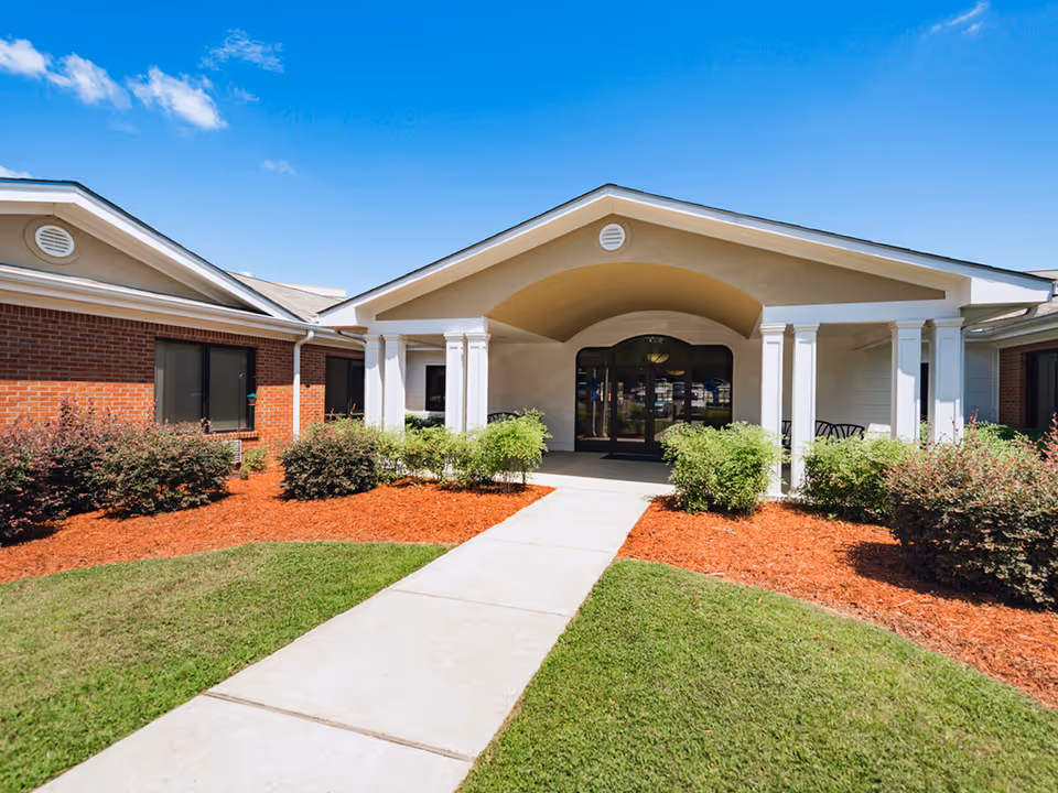 Front entrance of Arrington Living Center with a curved portico, glass doors, and landscaped walkway.