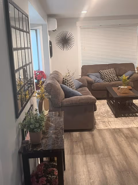 Cozy living room with brown sectional sofa, coffee table, and plants.