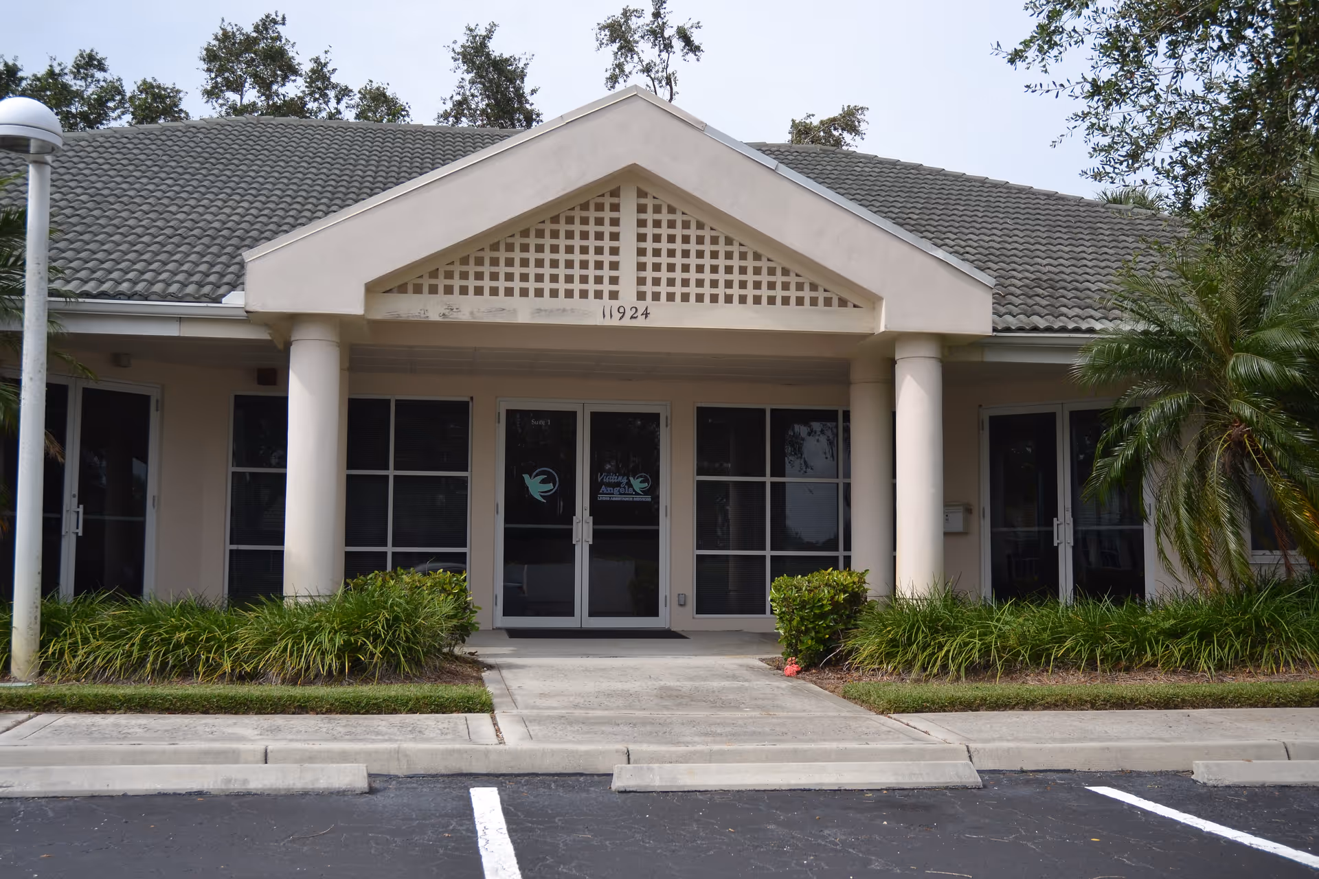 Front entrance of a beige, single-story senior care facility with glass doors and columns.