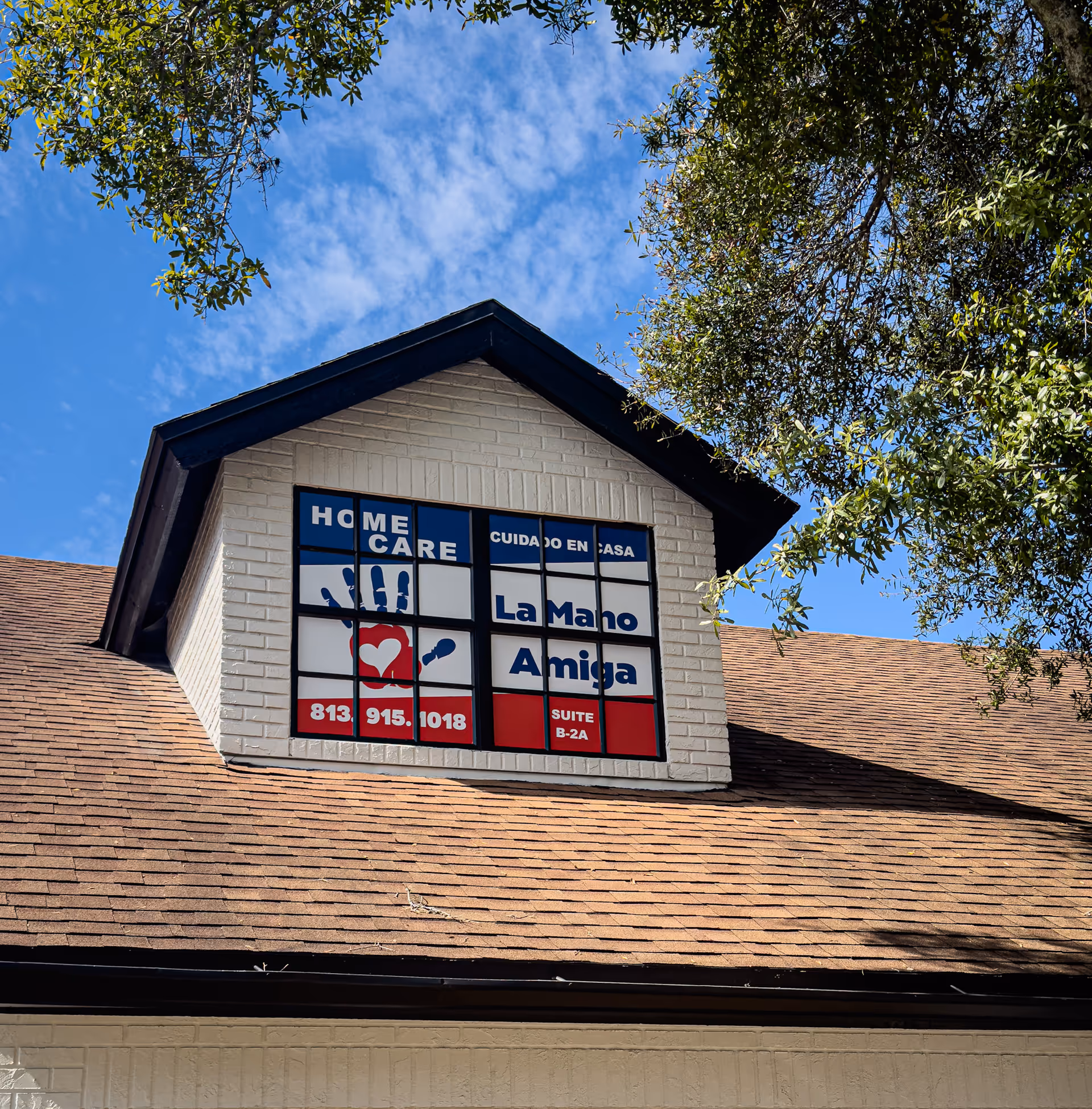 Exterior view of a white brick facility featuring La Mano Amiga sign on the front.