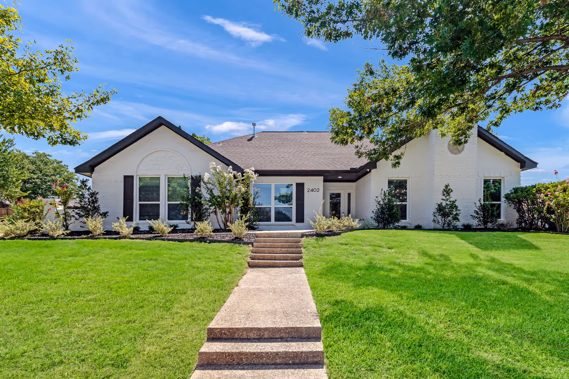 White, single-story senior living facility with a front entrance, steps, and green lawn.