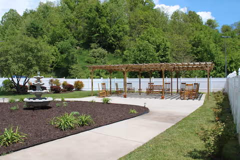 Outdoor courtyard with a wooden pergola, seating, a fountain, and landscaped garden.