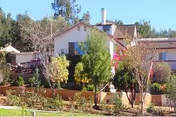 Front view of Huntington Manor senior living facility with trees and a patio.