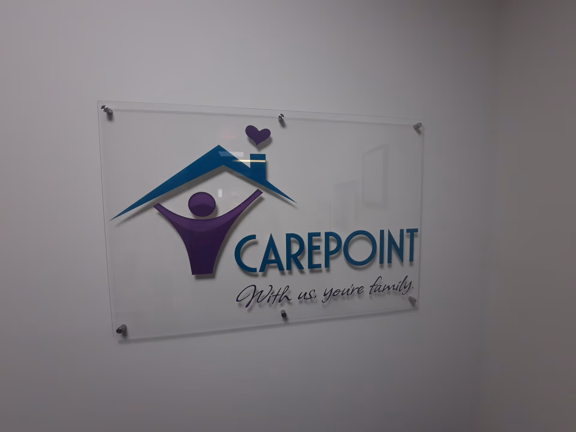 Interior wall sign displaying Carepoint logo with house roof and slogan.