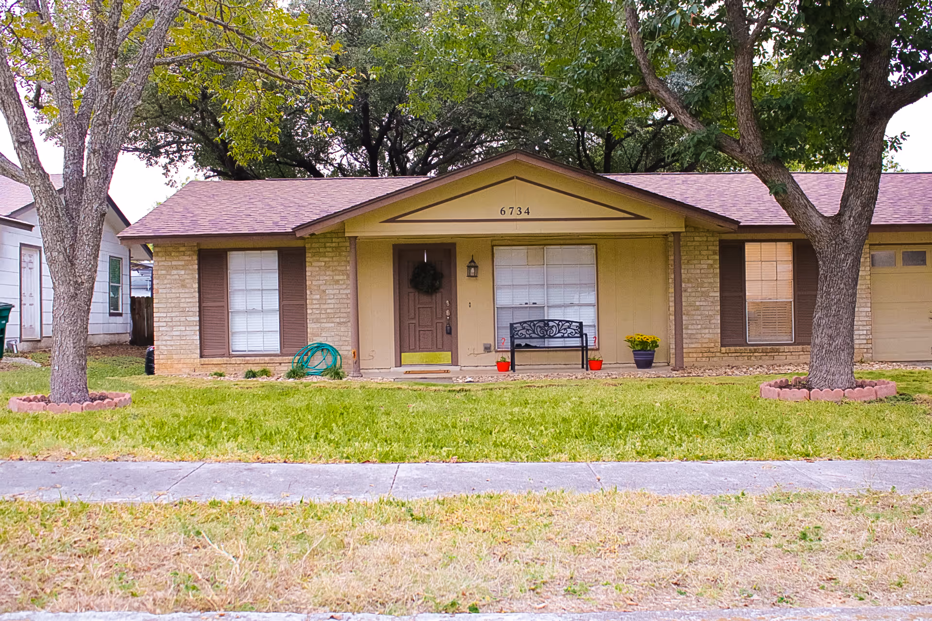 Front view of a single-story care home with porch, benches, and trees.