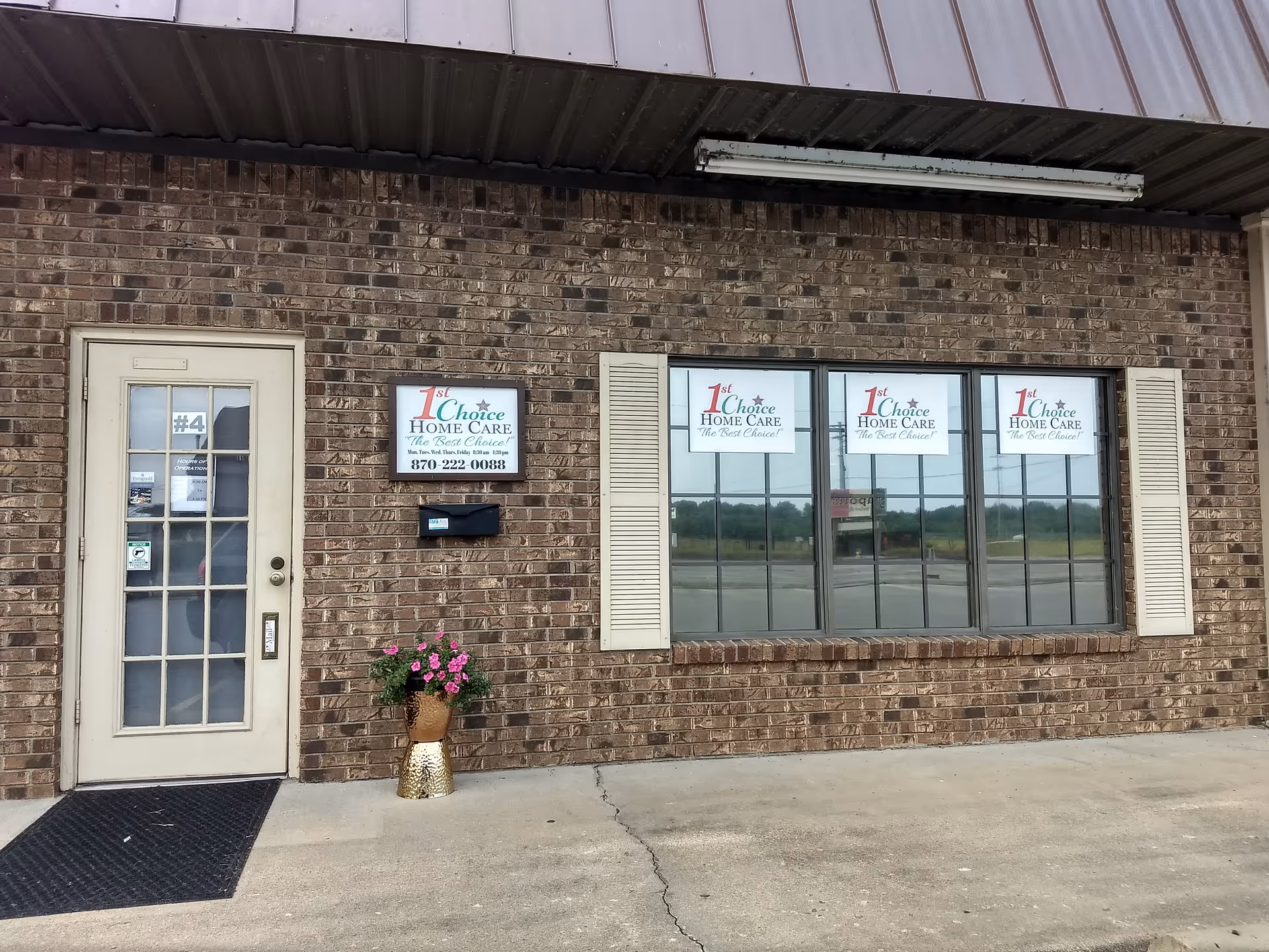 Exterior brick building with a door and large window displaying 1st Choice Home Care signs.