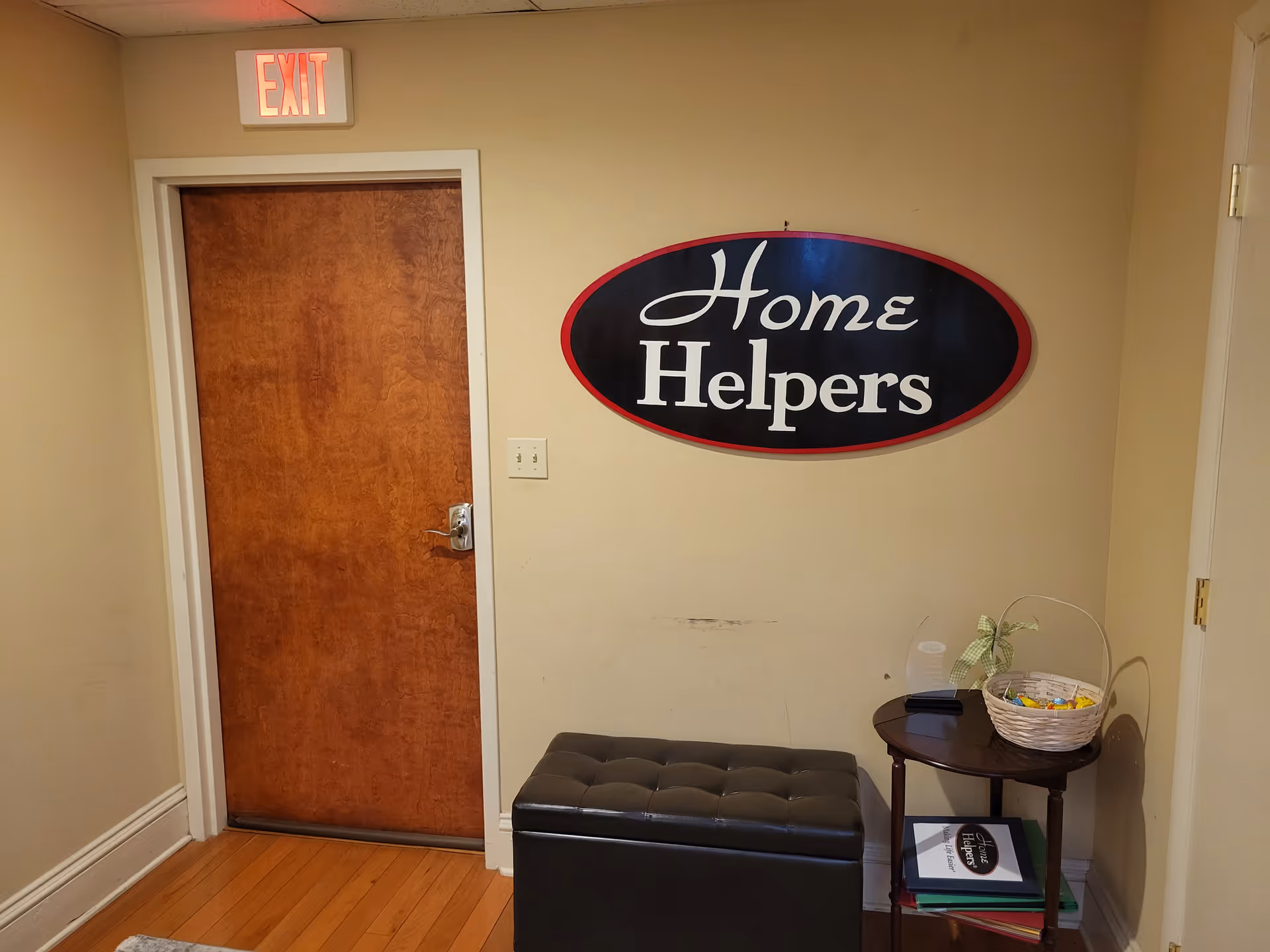 Interior hallway with a wooden door, exit sign, and Home Helpers sign on wall.