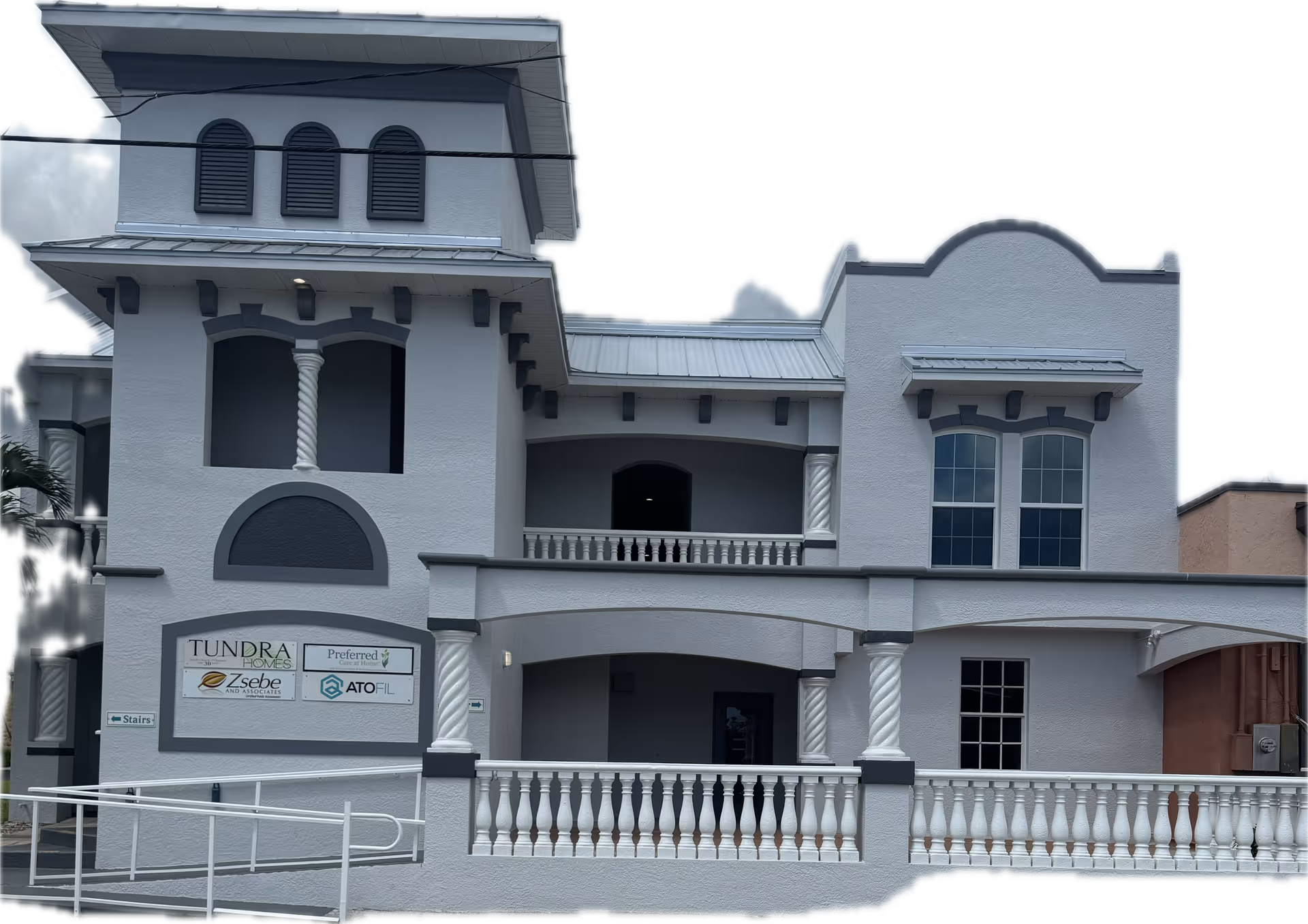Exterior view of a light-colored, two-story senior living building with arches and balcony.