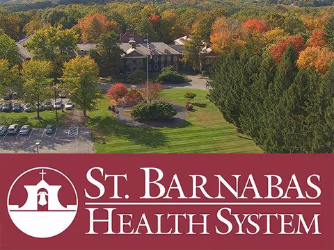 Aerial view of St. Barnabas Health System campus with trees, lawn, and a front building.