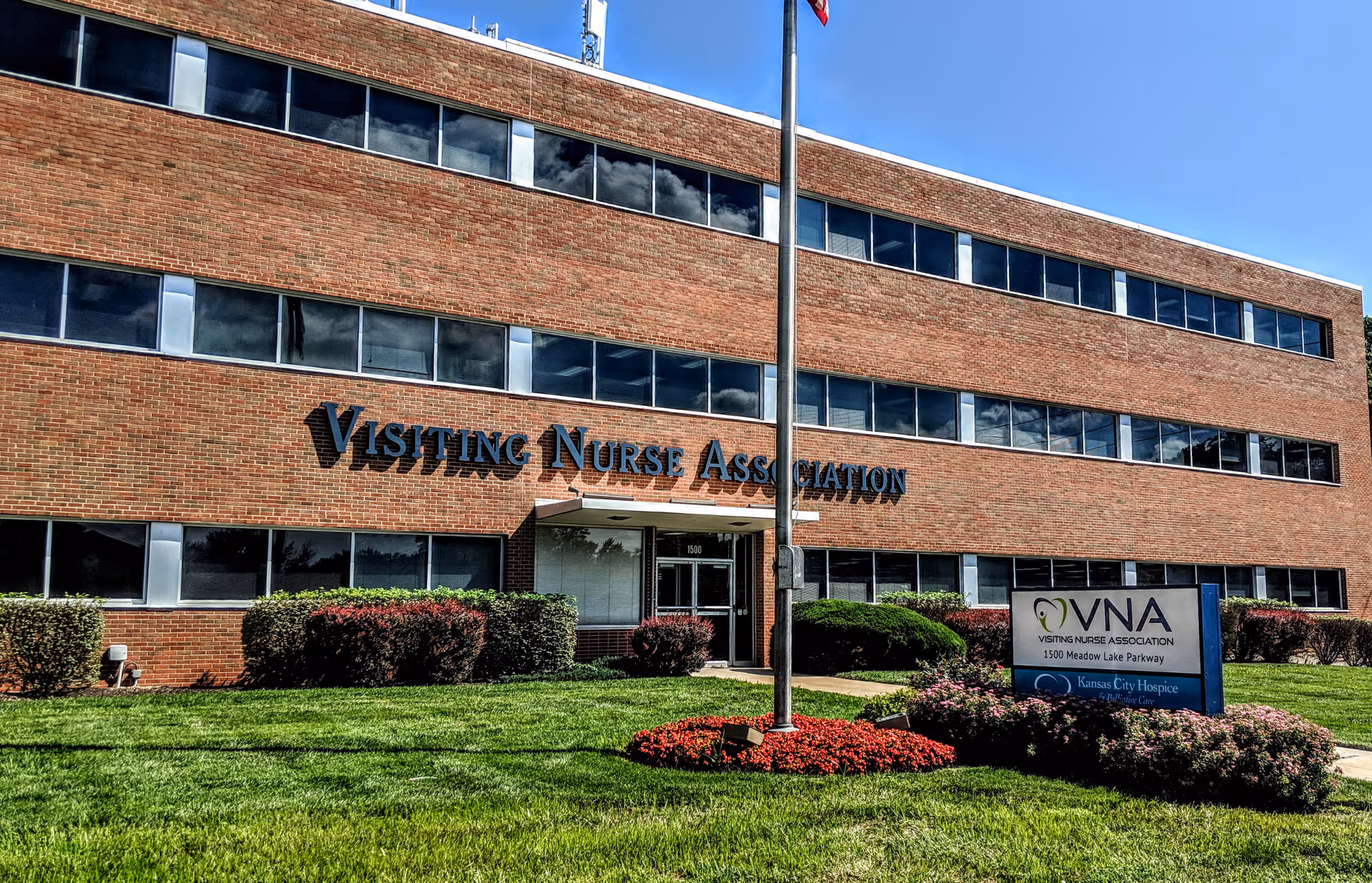 Brick building facade with Visiting Nurse Association sign and landscaped front lawn.