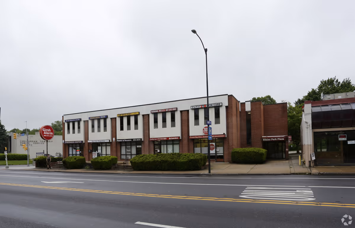 Exterior view of a brick storefront row with multiple signs along a street.