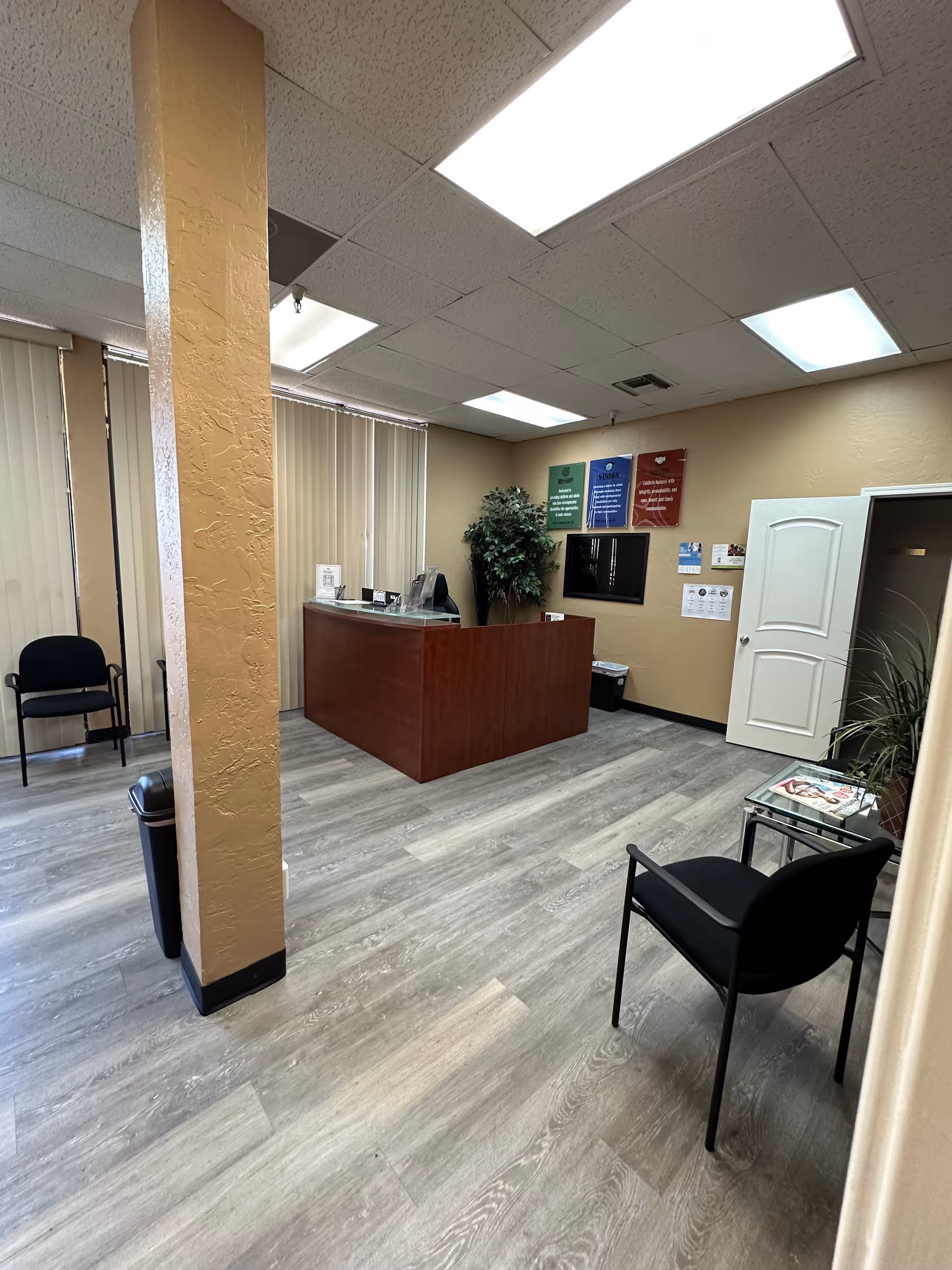 Reception area of a senior care facility with a wooden desk, chairs, and a column.