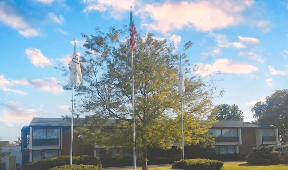 Front exterior of Flanagan Rehabilitation & Healthcare Center with flagpoles and trees.