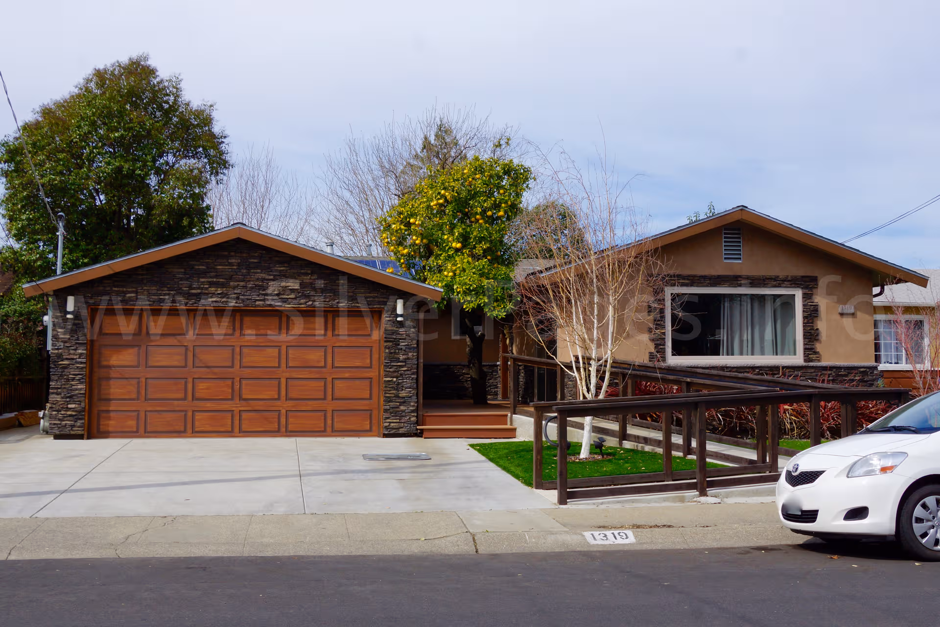 Single story senior living facility exterior with a two car garage and accessible ramp.