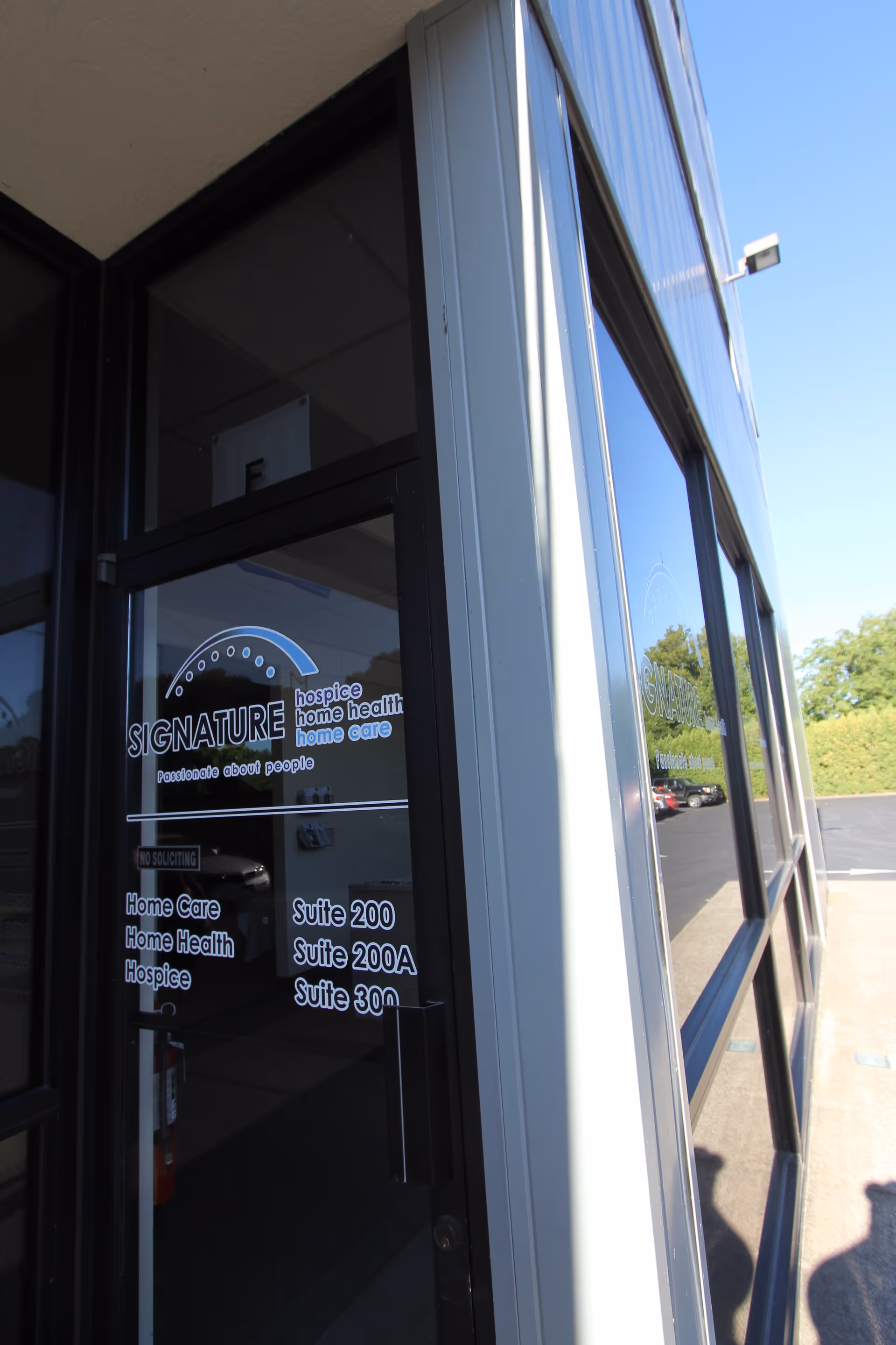 Glass entrance of a building with signage for Signature Hospice