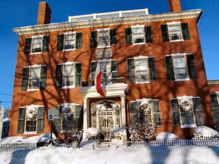Red brick building with white trim, snow-covered steps, flag at the entrance.