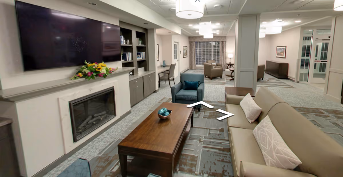 Spacious Regency at St. Clair Shores lounge with sofas, coffee table, fireplace, and TV.