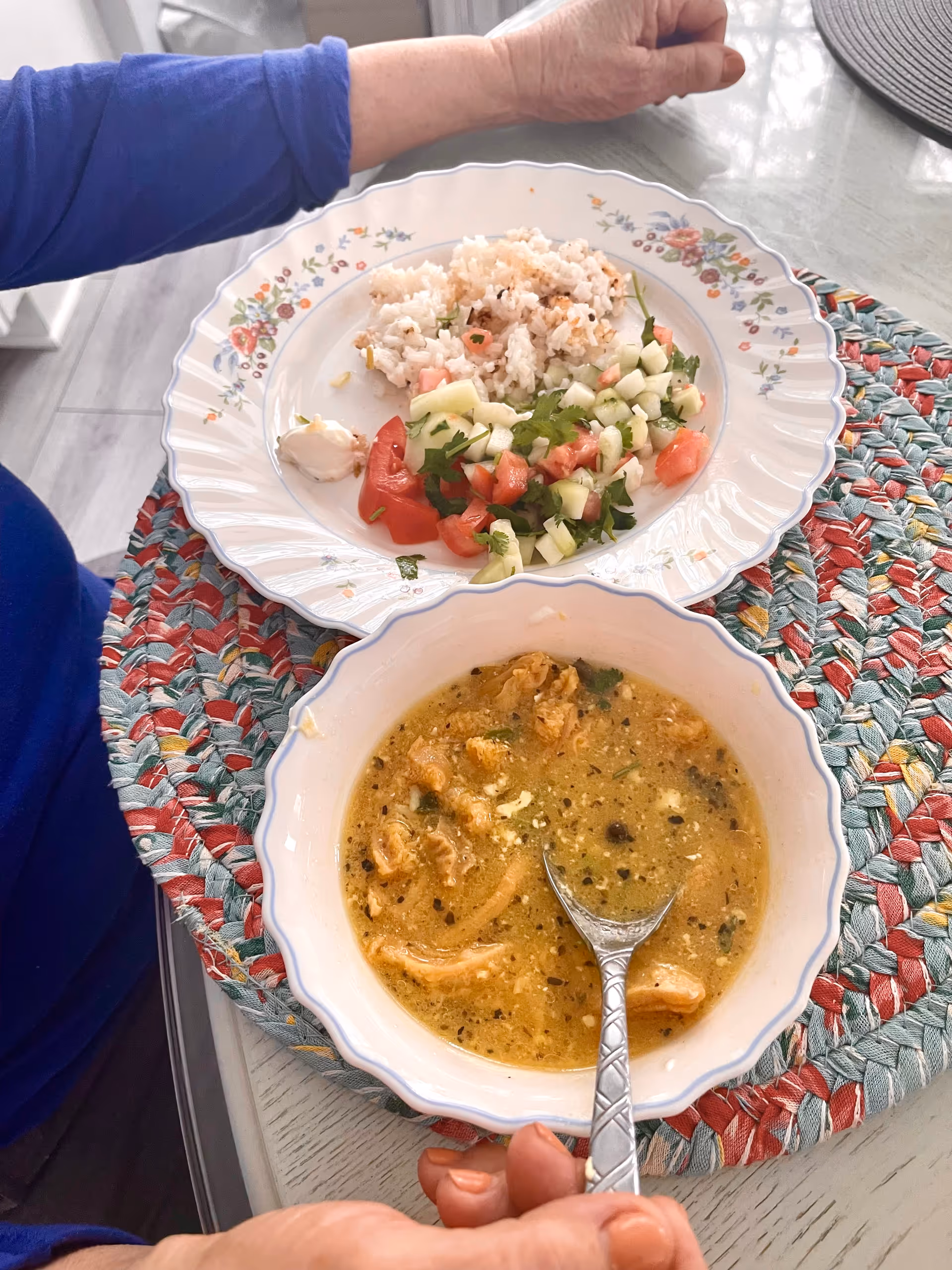 Meal setup in dining room: plate of salad and bowl of soup on patterned table.